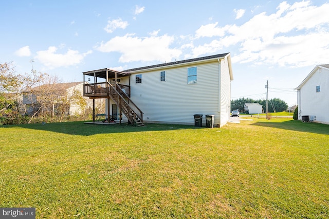 rear view of house featuring a lawn, a wooden deck, and central AC