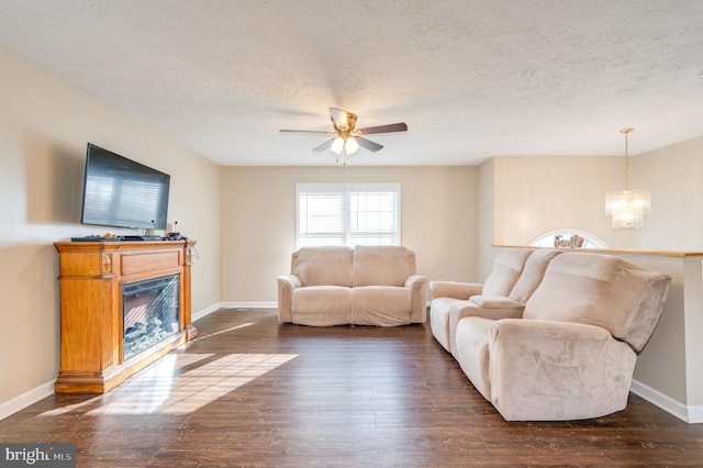 living room featuring ceiling fan with notable chandelier, a textured ceiling, and dark hardwood / wood-style floors