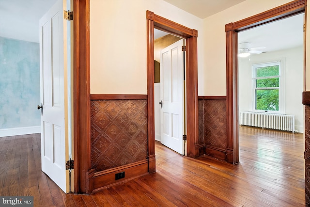 hall with radiator heating unit and wood-type flooring