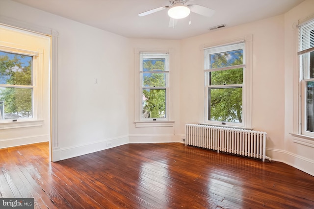 empty room with radiator heating unit, ceiling fan, and dark wood-type flooring