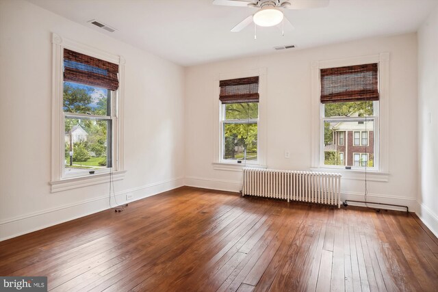 empty room featuring ceiling fan, dark hardwood / wood-style flooring, and radiator