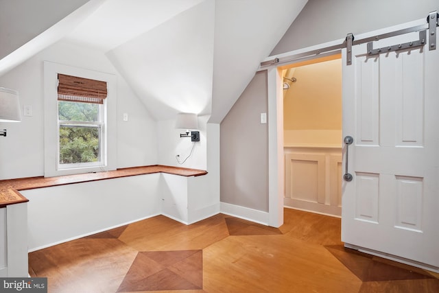 additional living space with a barn door, hardwood / wood-style flooring, and lofted ceiling