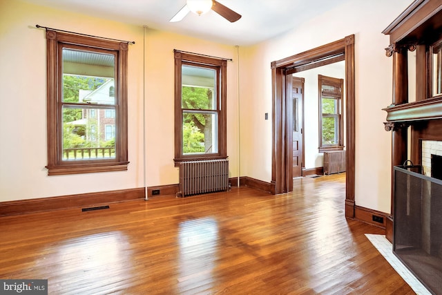 interior space with a wealth of natural light, radiator heating unit, and hardwood / wood-style flooring