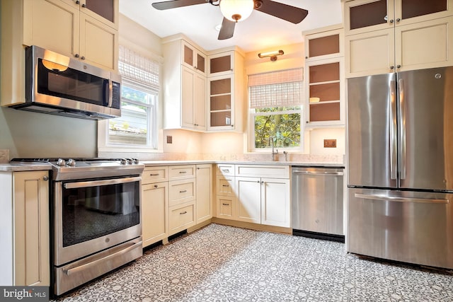 kitchen with appliances with stainless steel finishes, ceiling fan, cream cabinets, and sink