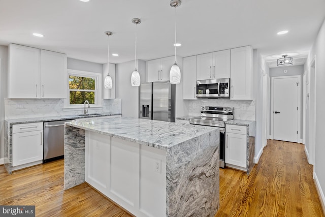 kitchen featuring white cabinetry, stainless steel appliances, a center island, and light hardwood / wood-style flooring