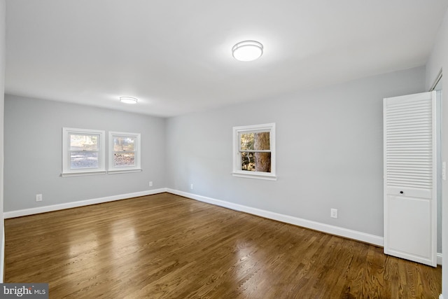 spare room with dark wood-type flooring and plenty of natural light