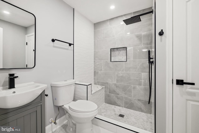 bathroom with a tile shower, vanity, and toilet