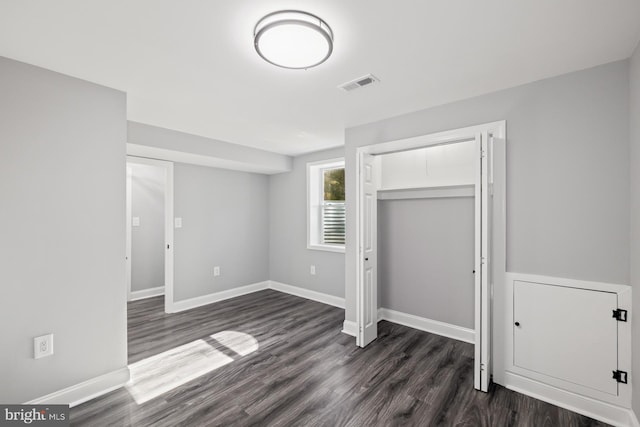 unfurnished bedroom with a closet and dark hardwood / wood-style floors