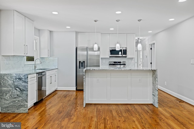 kitchen featuring white cabinetry, stainless steel appliances, a center island, and light hardwood / wood-style flooring