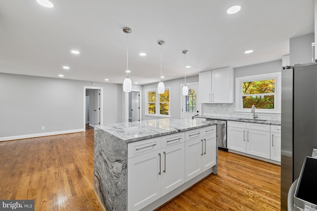 kitchen with white cabinetry, hanging light fixtures, a center island, and stainless steel appliances