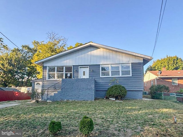 bungalow-style home with a front lawn and fence