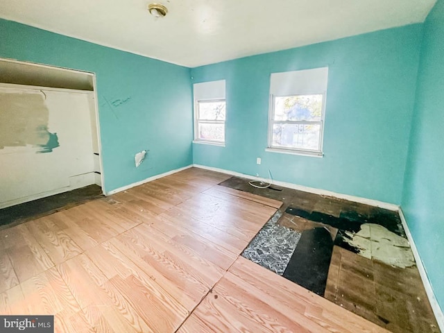 spare room with baseboards and wood finished floors