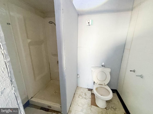 bathroom with a shower stall, marble finish floor, and toilet