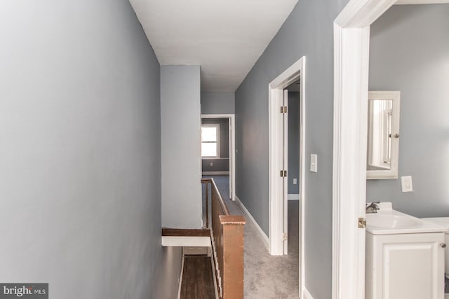 hallway with sink and dark carpet