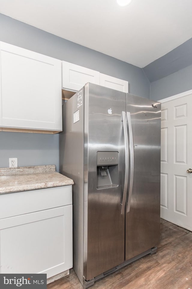 kitchen with white cabinets, dark hardwood / wood-style flooring, vaulted ceiling, and stainless steel fridge