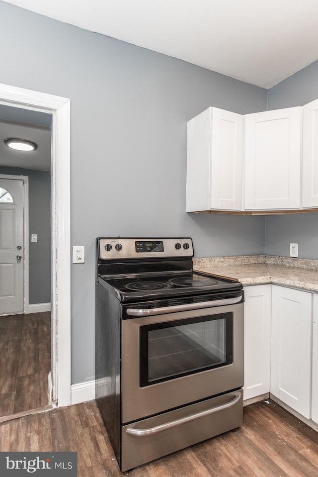 kitchen featuring dark hardwood / wood-style floors, white cabinetry, and electric range