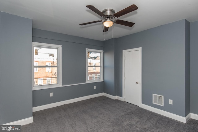 spare room with ceiling fan and dark colored carpet