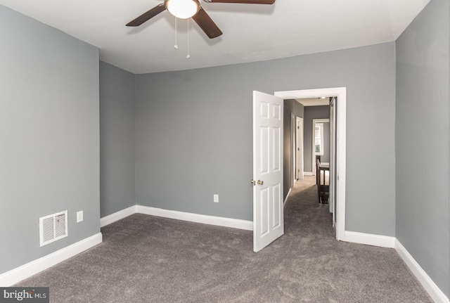 spare room featuring ceiling fan and dark colored carpet