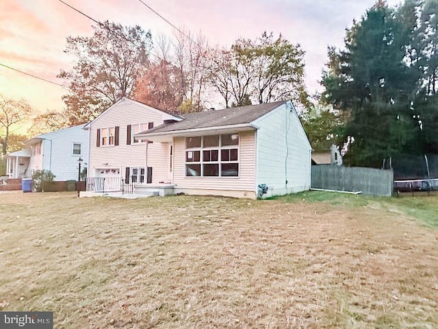 back house at dusk with a trampoline and a lawn