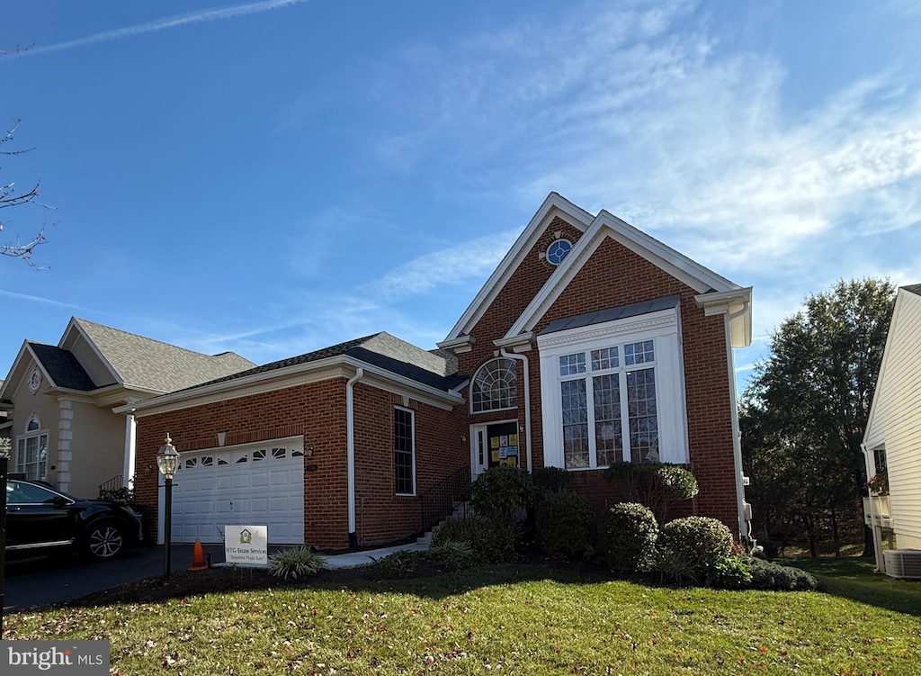 view of front of home with a garage, cooling unit, and a front lawn