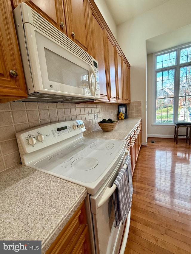 kitchen with light hardwood / wood-style flooring, tasteful backsplash, and electric range