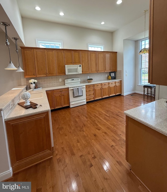 kitchen featuring hardwood / wood-style floors, hanging light fixtures, stove, and tasteful backsplash