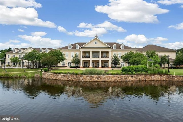 back of property featuring a water view and a lawn