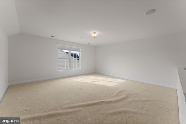 carpeted empty room featuring vaulted ceiling