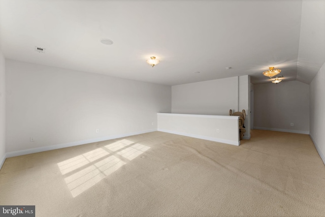 spare room featuring light colored carpet and vaulted ceiling