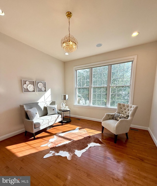 living area featuring hardwood / wood-style floors and an inviting chandelier