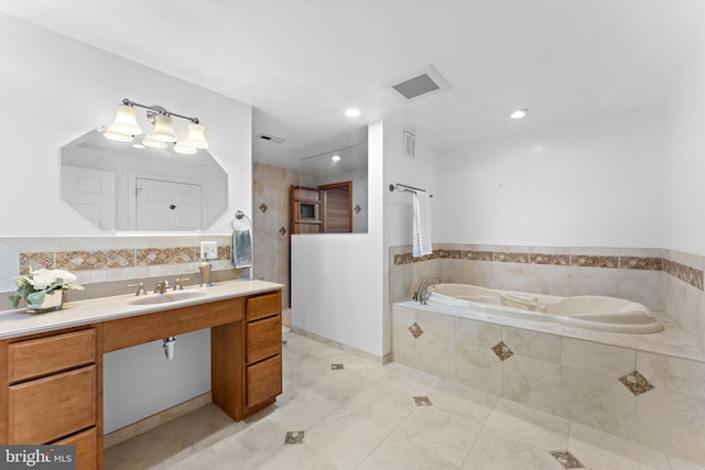 bathroom featuring a relaxing tiled tub, tile patterned flooring, and vanity