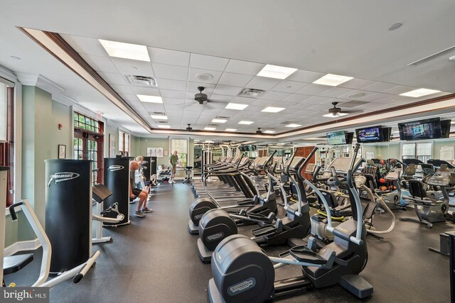 exercise room with ceiling fan, a paneled ceiling, and ornamental molding