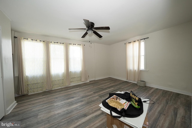 empty room featuring dark wood-type flooring, ceiling fan, and a healthy amount of sunlight