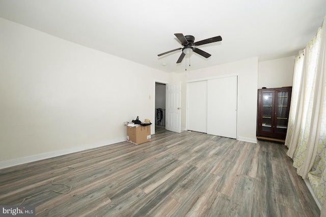 unfurnished bedroom with dark hardwood / wood-style flooring, a closet, and ceiling fan