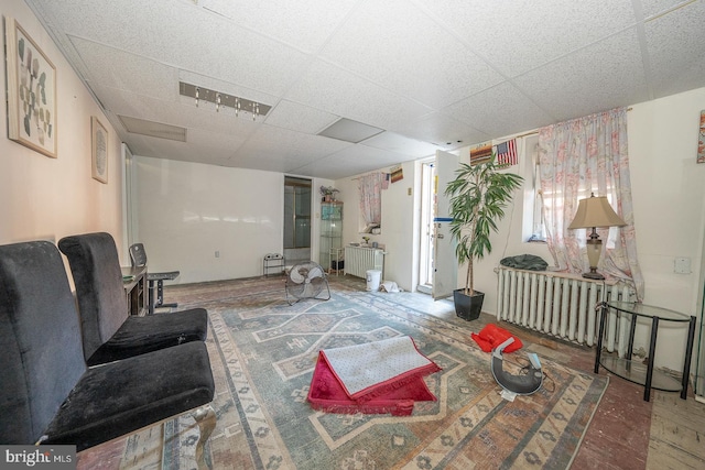 living room featuring wood-type flooring and a paneled ceiling