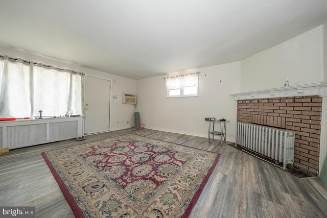 living room with hardwood / wood-style floors, a brick fireplace, a wall mounted air conditioner, and radiator