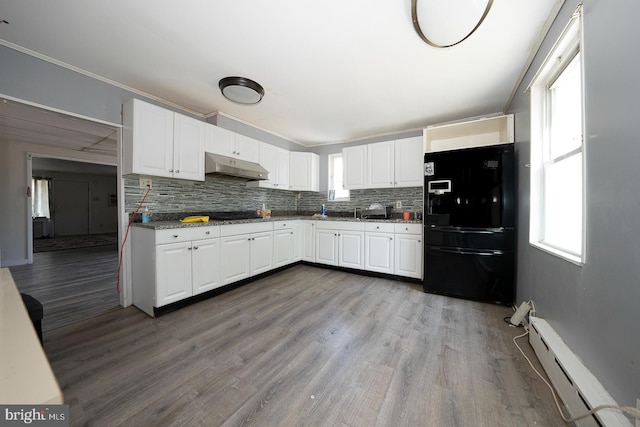 kitchen featuring plenty of natural light, white cabinetry, a baseboard heating unit, and black fridge with ice dispenser