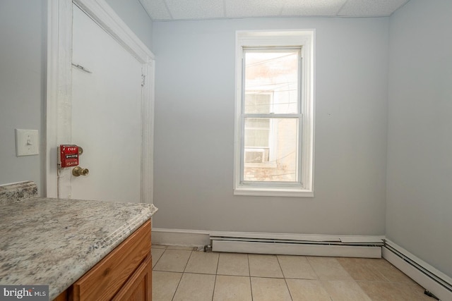 bathroom with a paneled ceiling, tile patterned floors, and a baseboard heating unit