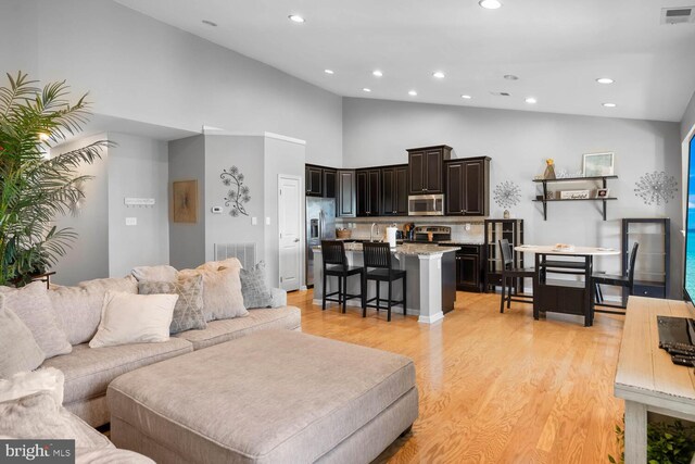 living room featuring high vaulted ceiling and light hardwood / wood-style floors