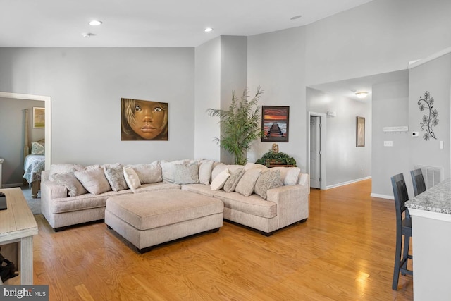 living room with high vaulted ceiling and light wood-type flooring