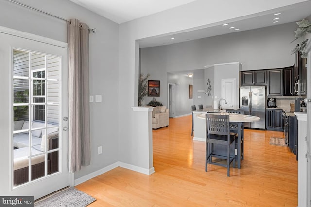 kitchen with appliances with stainless steel finishes, a breakfast bar, and light wood-type flooring