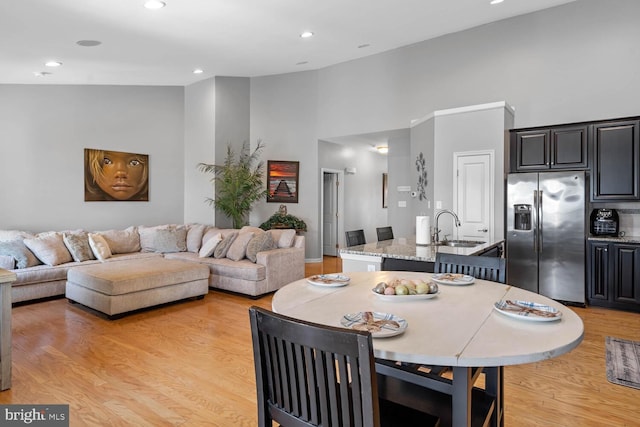 dining area with sink, high vaulted ceiling, and light hardwood / wood-style floors