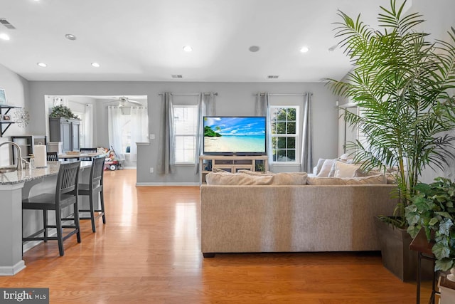 living room with sink, light wood-type flooring, and ceiling fan