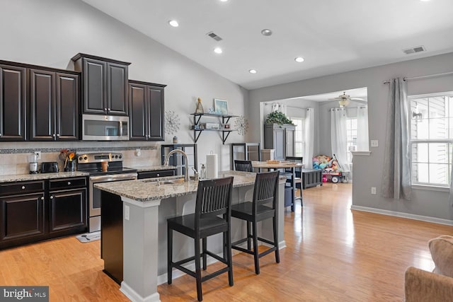 kitchen featuring appliances with stainless steel finishes, sink, a kitchen breakfast bar, vaulted ceiling, and a center island with sink