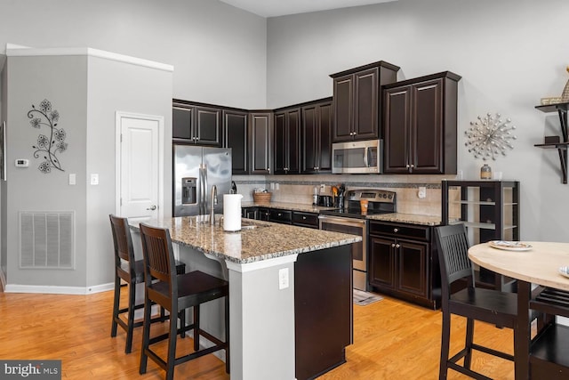 kitchen featuring light stone counters, a kitchen island, appliances with stainless steel finishes, light hardwood / wood-style flooring, and sink