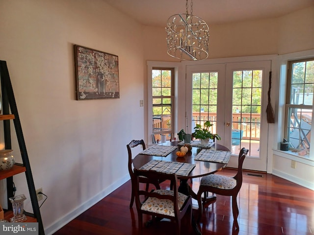 dining area with french doors, dark hardwood / wood-style flooring, and an inviting chandelier