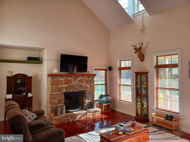 living room featuring a stone fireplace, hardwood / wood-style flooring, and a towering ceiling