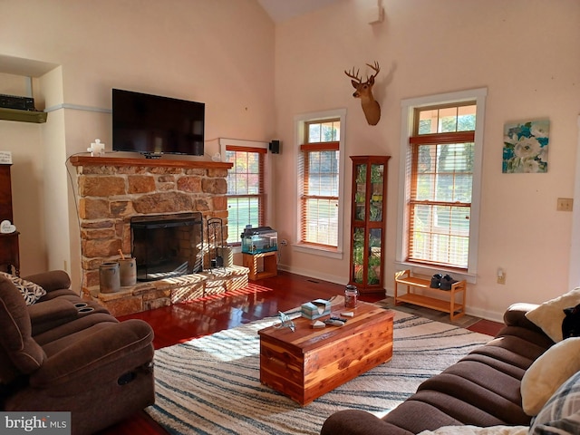 living room with a healthy amount of sunlight, a stone fireplace, and hardwood / wood-style floors