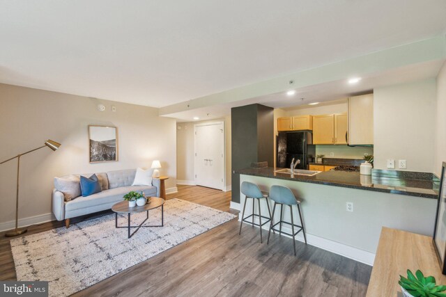 kitchen with dark hardwood / wood-style flooring, kitchen peninsula, sink, and black fridge