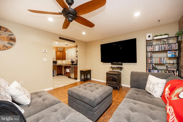 living room featuring light hardwood / wood-style floors, ceiling fan, and a wood stove